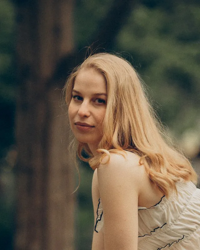 Sofiia, the piano teacher who made Chenko, sitting on a garden bench